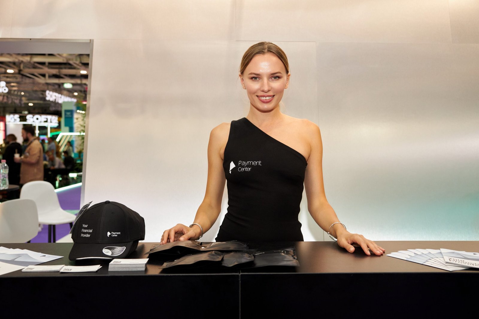 Smiling hostess representing Payment Center at an exhibition booth with promotional materials
